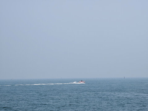 Minimalist Seascape with A Distant Soft Pink Boat Cruising On Calm Grey-Blue Ocean Vast Empty Sky And Sea