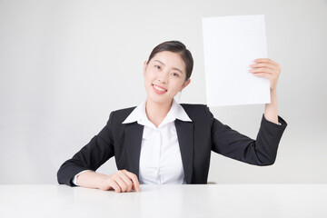 Smiling businesswoman holding blank paper at desk