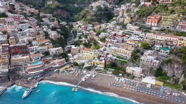Aerial Drone Close View of Positano with Chiesa Santa Maria Assunta Dome, Crowded Beach and Colourful Buildings, Amalfi Coast Italy