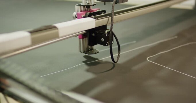Close up of precision machine head drawing pattern on fabric in factory