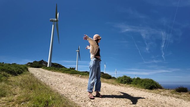 Windmill on a farm, white woman working in clean energy and electricity generation using wind turbines in Spain. Renewable energy, agricultural engineer, environment, and safety equipment
