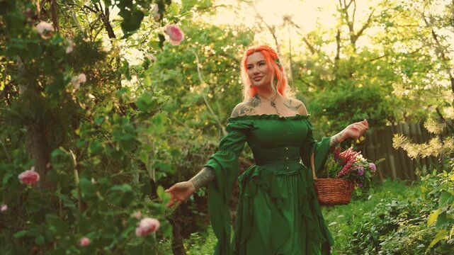 Happy fantasy woman healer holds basket herbs for essential oil. fairy elf girl herbalist hand touching tea rose flowers walking in sun rays magic light forest summer nature grass trees. green dress.