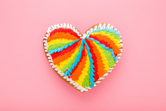 Heart shape colorful gingerbread cookie on light pink table background. Pastel color. Closeup. Sweet snack. Flat lay. Top down view.