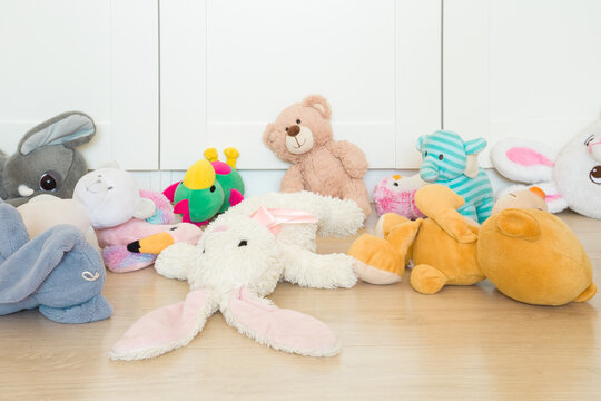 Different colorful soft animal toys cluttered on wooden floor at nursery room. Closeup. Front view.