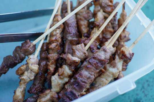Delicious Grilled Chicken and Pork Skewers in a White Container