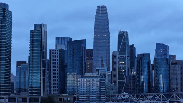San Francisco skyline at dusk with the iconic Salesforce Tower and striking glass skyscrapers. Blue hour lighting highlights modern architecture in a cinematic wide angle cityscape shot.