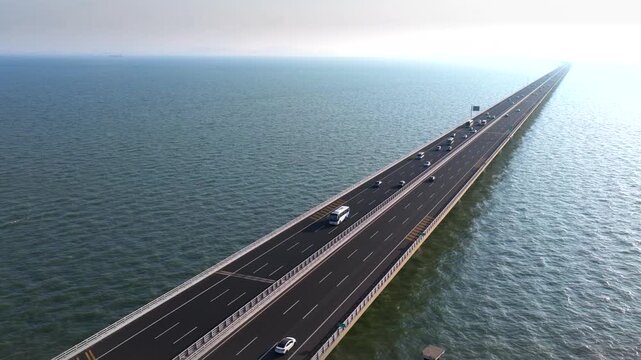 Aerial view of a magnificent sea-crossing bridge in China; the bridge spans the ocean and extends into the distance under a blue sky with white clouds.
