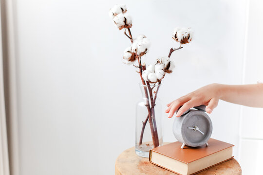 Hand turning off an alarm clock in cozy bedroom interior. Awakening, sleep quality and woman morning routine. Concept of biological clock, circadian rhythm
