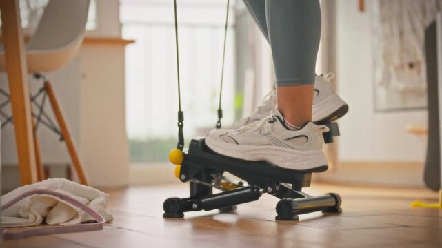 In bright home gym, female athlete wearing leggings intensely works out stepper, exemplifying affordable cardio exercise. She efficiently maintains physical fitness at home with each deliberate step