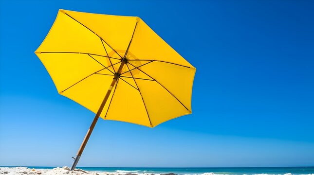 Yellow beach umbrella with wooden pole on white sand under clear blue sky. Low angle view of sunshade inner ribs against a bright tropical horizon on a sunny summer day.
