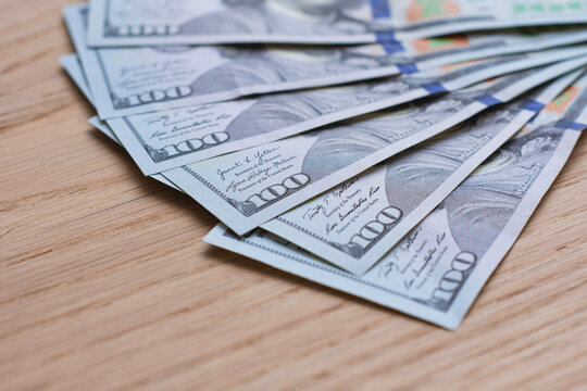 US dollar banknotes, one hundred dollar bills on a wooden surface with copy space. Finance, cash payment, personal savings, investment, banking, wealth and money management concept for business use.