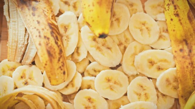 Sliced ​​ripe bananas are arranged in neat rows on a wooden table next to their peels. A natural, minimalist background and texture for designs, blogs, and banners about healthy eating