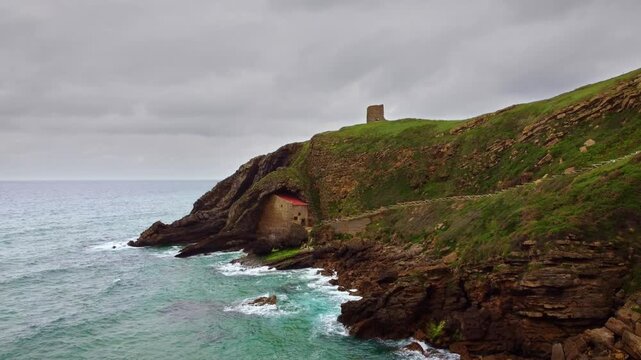 Aerial drone view of Santa Justa Hermitage, a unique chapel built inside a coastal cliff cave in Ubiarco, near Santillana del Mar, Cantabria, Northern Spain. High quality 4k footage