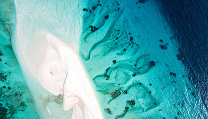 Fototapeta premium Abstrakte Luftaufnahme von oben auf ein flaches tropisches Riff mit einer Sandbank, sanfte Wasserrippeln über kreideweißen und aquamarinfarbenen Strukturen, helles Design