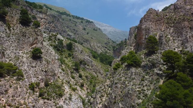 Aerial view of suspension bridge of 'El Saltillo Canillas de Aceituno' in the beautiful mountain landscape of Canillas de Aceituno on a sunny day, Malaga, Spain