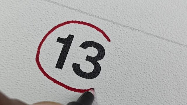 Close-up of Red Pen Marking Date 13 on Calendar. Deadline and Reminder Concept