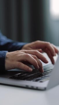 Woman works on a laptop keyboard in a candid setting during the day.
