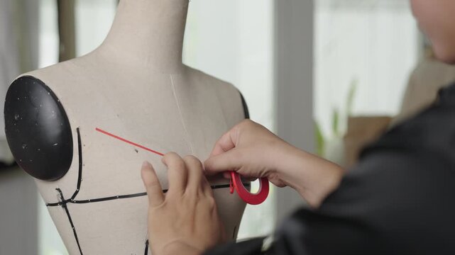 Fashion designer applying style tape to dress form mannequin for custom wedding dress pattern making
