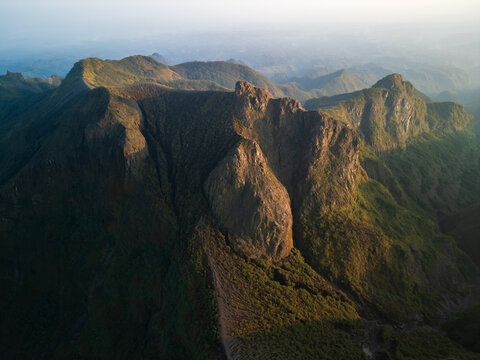 Aerial view of the rugged volcanic crater and rocky slopes of Mount Kelud, illuminated by soft golden light in Garum, East Java, Indonesia.