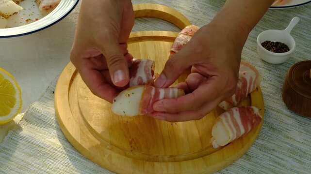 A chef wraps strips of raw cod in thinly sliced ​​bacon for grilling. Step-by-step video recipes. Horizontal video.