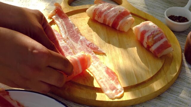 A chef wraps strips of raw cod in thinly sliced ​​bacon for grilling. Step-by-step video recipes. Horizontal video.