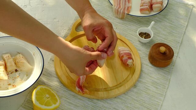 A chef wraps strips of raw cod in thinly sliced ​​bacon for grilling. Step-by-step video recipes. Horizontal video.