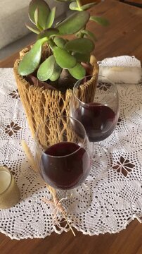 Romantic home setting with two glasses of red wine on a wooden table with elegant candles