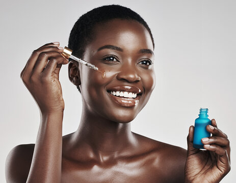 Happy African Woman Applying Face Serum with a Dropper for Glowing Skin
