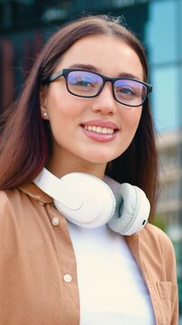 Close-up of Caucasian brunette woman in a blue shirt working on a wireless laptop outdoors in a city park, with a modern building in the background. Concept of remote work and people