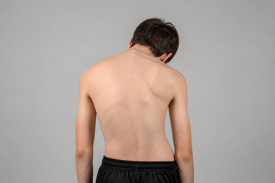 A man is shown from the back, standing against a plain gray background.