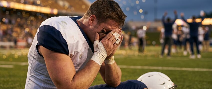 Emotional American football player covering face after difficult game. Concept of sports disappointment, emotional pressure, athlete recovery, football defeat and mental resilience. Banner