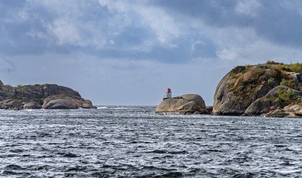 Coastal Lighthouse on Rocky Island Overlooking Turquoise Sea Under Cloudy Sky, Stavern, Norway