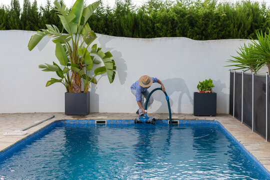 Pool worker deploying robotic pool cleaner into swimming pool