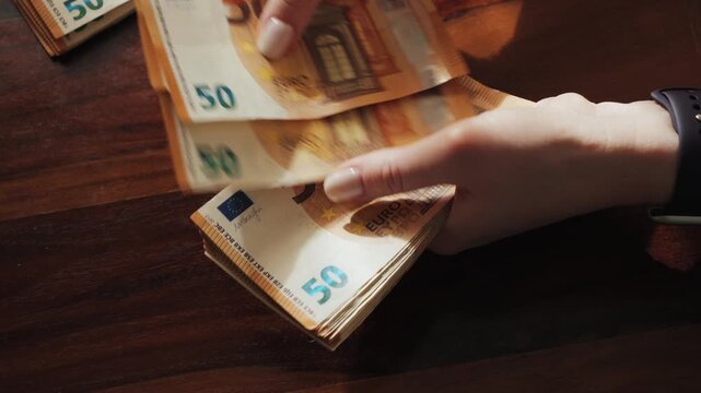 Hands of a woman counting many 50-euro bills. Woman counts banknotes salary or unemployment benefit. High quality 4k footage