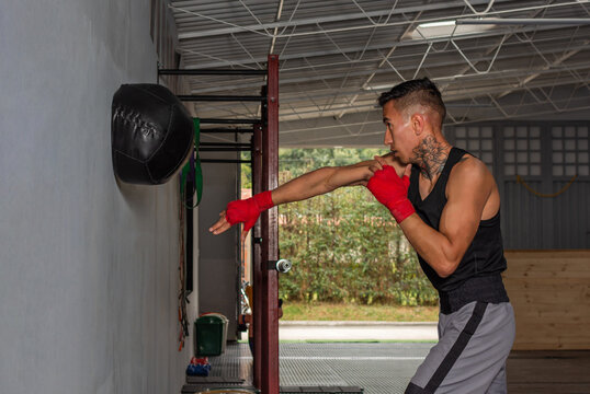 Focused Hispanic boxer performing medicine ball power drill in gym