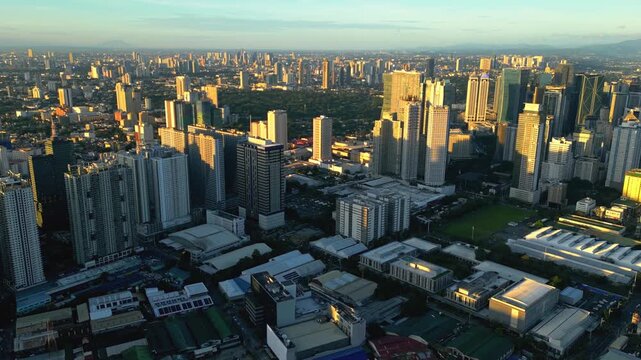 Slow orbit drone footage around the Shaw Boulevard urban district in Mandaluyong and Pasig Philippines featuring glowing roads, high rise buildings, and Ortigas daytime skyline elements.