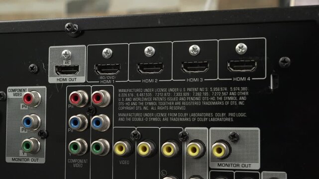 Hand pulls an HDMI monitor out cable from a row of labeled HDMI and legacy AV ports on a consumer receiver.