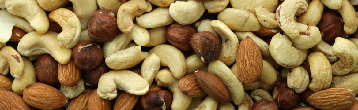 Detailed view on almond and cashew nuts in big pile on table close up