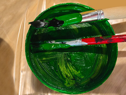 Green paint and brushes resting in container