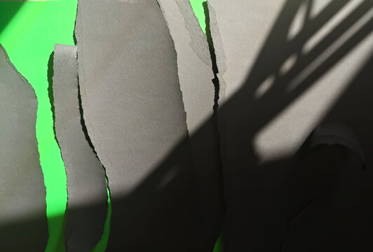 Torn paper pieces revealing green screen with shadows