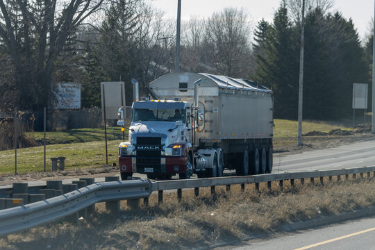 Quebec, Canada, 24 April 2026 : A MACK semi-truck with a silver dump trailer drives on a highway.