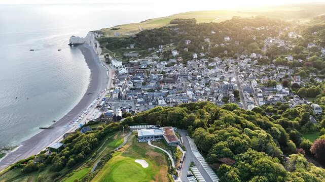 Golden hour aerial over Etretat France chalk cliffs and seaside town
