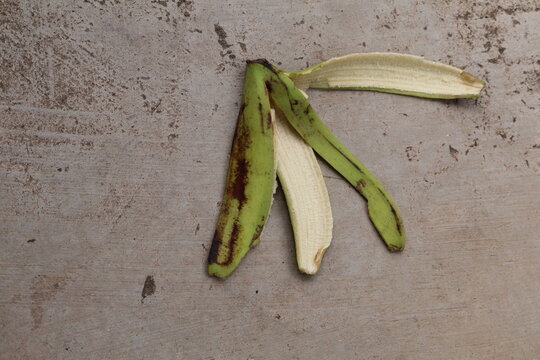 Green Ambon banana peel resting naturally on earthy ground