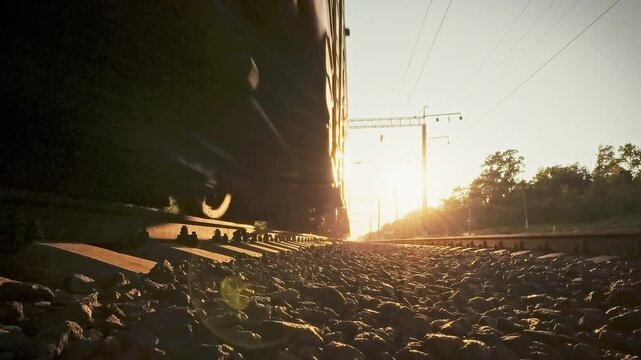 Close-up of freight train wheelsets over rails and sleepers on a sunny day. The concept of industrial power and the scale of the country's railway freight traffic