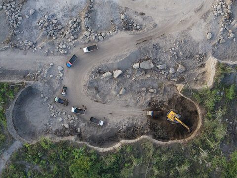 Aerial view of Sand and Stone Quarry with an excavator loading sand into trucks in a rural landscape in Manisrenggo, Central Java, Indonesia.