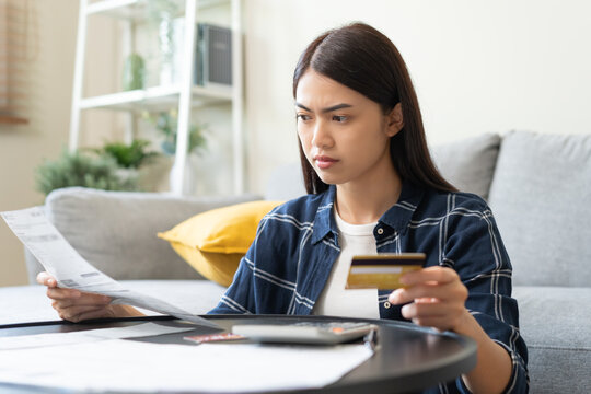 Business financial concept, stressed asian young woman hand checking list statement of credit card  for calculate accounting expense, tax for payment on due deadline, trying to find money to pay debt