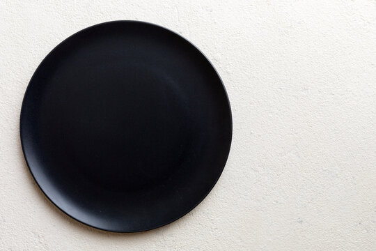 Top view of black plate on cement background. Empty space for your design