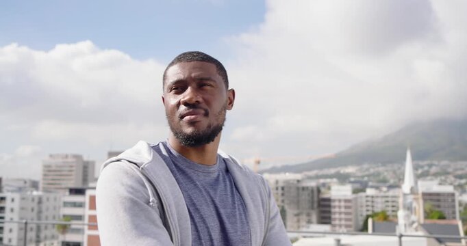 Mid-adult African man on roof parapet, surveying skyline, reflecting, turning toward camera
