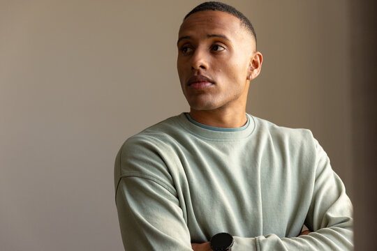 African American man standing arms crossed, looking right in room with sage sweatshirt, black watch