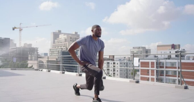 Adult African American man starting kettlebell lunges, swings and squats on rooftop near railing